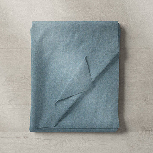 Folded blue fabric sample in plain cotton blend, placed on light wooden surface