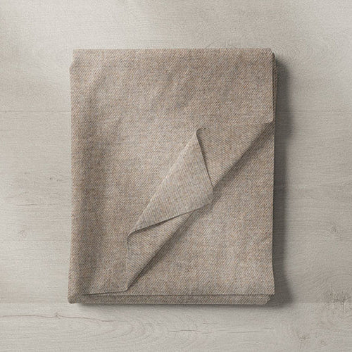 Natural linen blend fabric sample in beige tones, folded on wooden surface