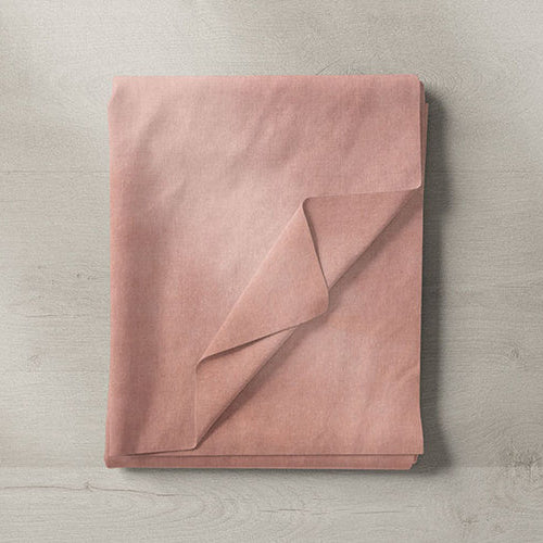 Folded pink fabric sample in soft blush tone on wooden background
