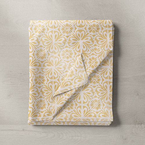 Folded yellow and white patterned fabric sample on wooden surface, cotton blend
