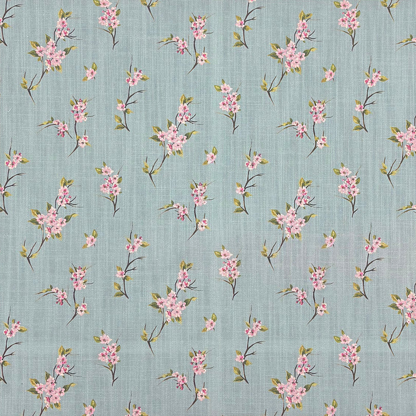 Close-up of Apple Blossom linen curtain fabric in Duck Egg with pink blossom print on a blue-green background