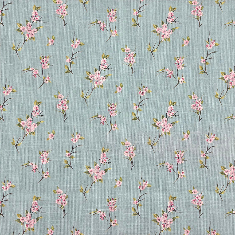 Close-up of Apple Blossom linen curtain fabric in Duck Egg with pink blossom print on a blue-green background
