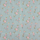 Close-up of Apple Blossom linen curtain fabric in Duck Egg with pink blossom print on a blue-green background