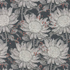 Flat lay of Barwick Midnight floral linen curtain fabric featuring grey protea blooms on a dramatic dark charcoal background