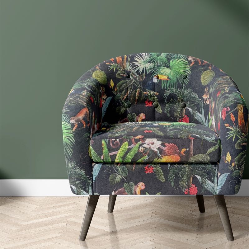 Jungle velvet upholstery fabric shown on a chair with tropical animal and leaf print