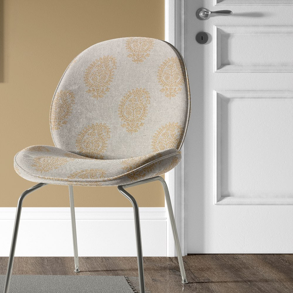 Kaveri Paisley Ochre upholstery fabric upholstered on a chair, creating a timeless vintage look