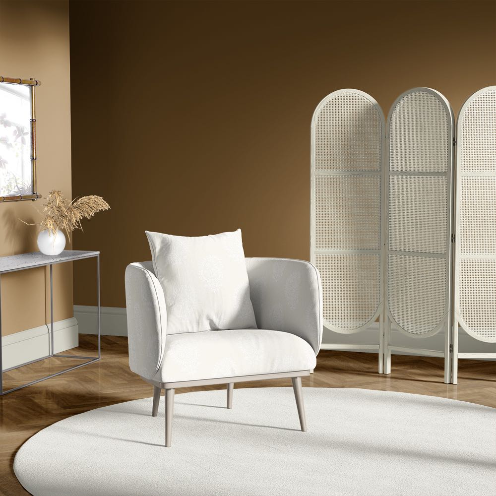 Armchair upholstered in paisley natural upholstery fabric, styled in a warm-toned living room with cane screen and neutral accents