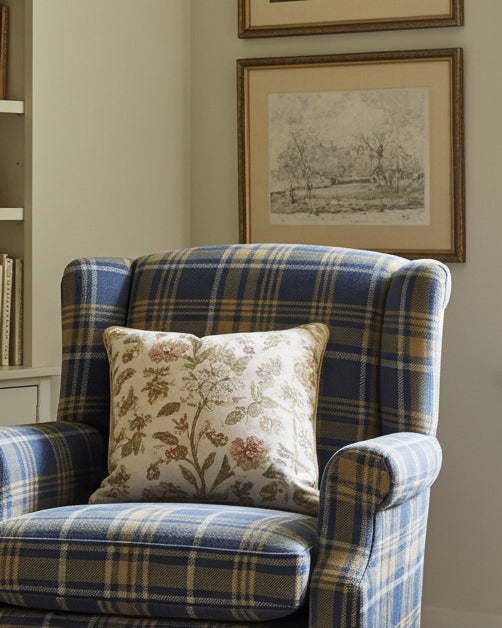 Blue and yellow plaid upholstery fabric on a classic armchair in a traditional reading nook with bookshelf backdrop