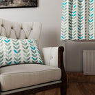 Turquoise and sage leaf curtain fabric used in a modern interior with matching cushion on a neutral armchair