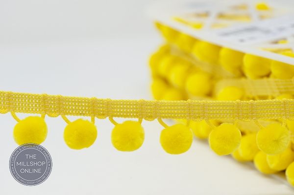 Vibrant yellow pom pom trim, ideal for adding a playful touch to crafts and garments