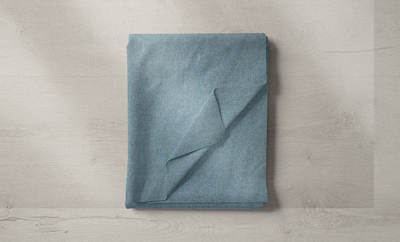 A layered display of blue fabrics, from soft linens to plush velvets, in navy, duck egg, and teal hues.