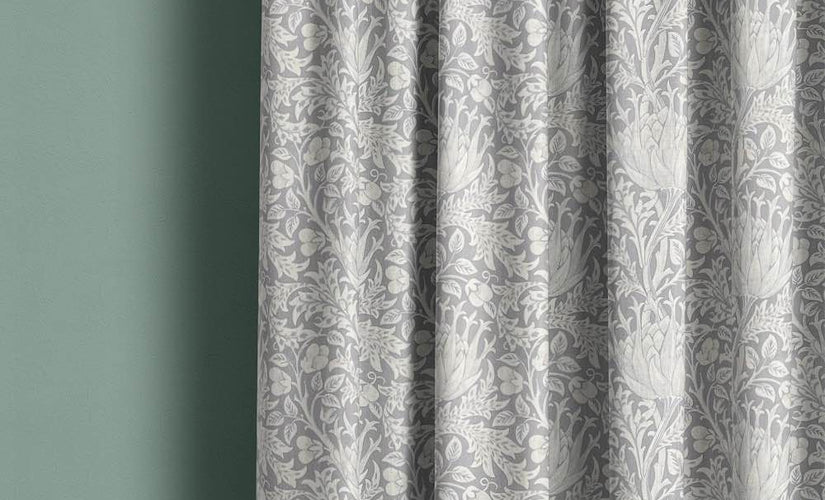 Grey made to measure curtains with subtle floral pattern hanging against pale green wall