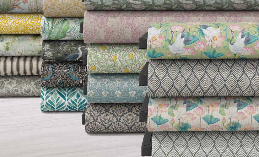 Stack of patterned and plain fabrics by the metre including florals, geometrics and textured upholstery materials