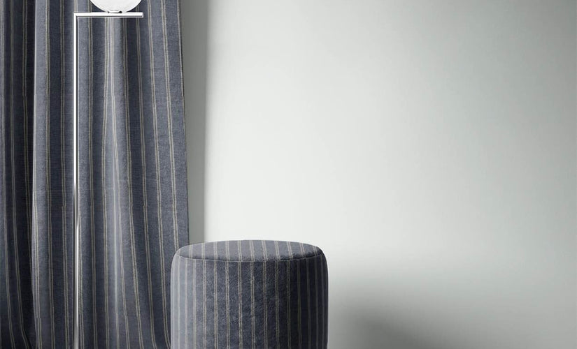 Denim blue curtain fabric with subtle stripe, styled with modern ottoman