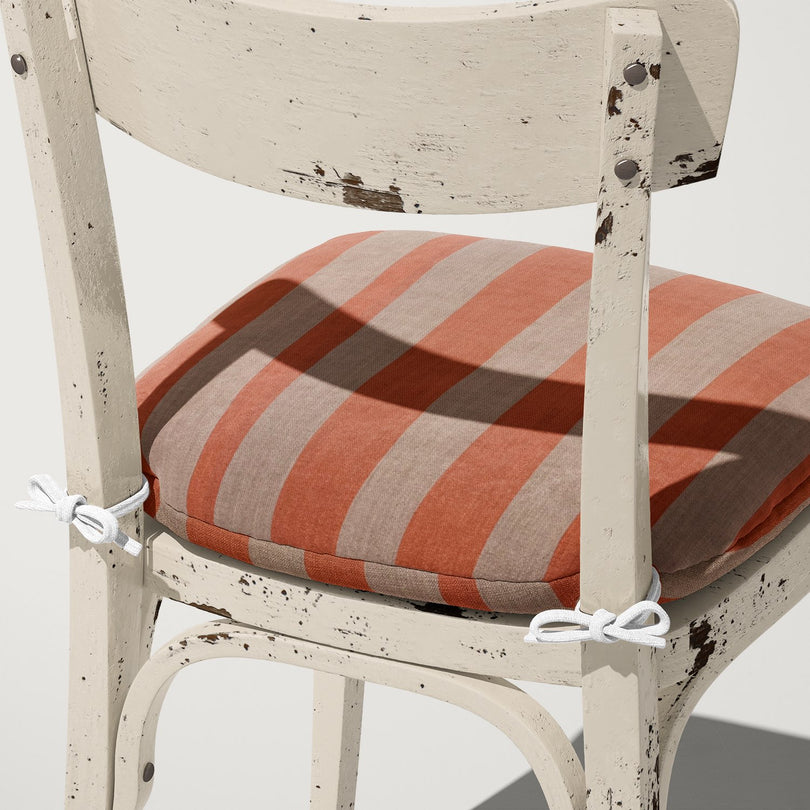 Peach Altena upholstery fabric shown on cushion – subtle coral stripe design on linen base