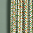 Avon multicoloured leaf curtain fabric shown as full-length curtains in a green interior