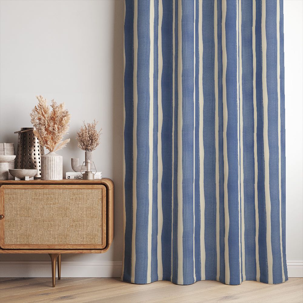 Fresno Stripe Blue linen curtain fabric shown as curtains with bold cobalt and ivory painterly stripes in a relaxed, modern interior