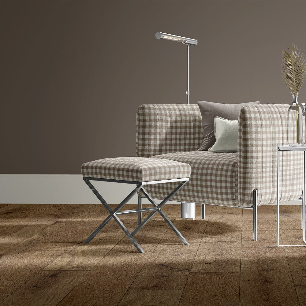Taupe gingham check upholstery fabric styled on a modern chair and footstool against a rich brown wall.