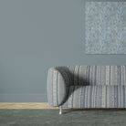 Khenifra Sapphire velvet upholstery fabric shown on a sofa with vertical kilim stripe design
