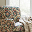 Bohemian-inspired floral upholstery fabric on a lounge chair, paired with a textured knit throw by a window