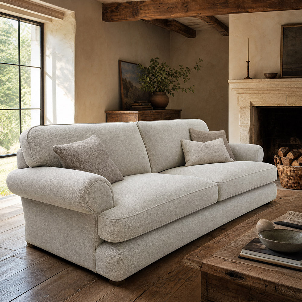 Norton Plain Upholstery Fabric sofa in natural beige upholstery fabric, displayed in a rustic country living room with exposed wooden beams, stone fireplace and warm neutral interior styling.