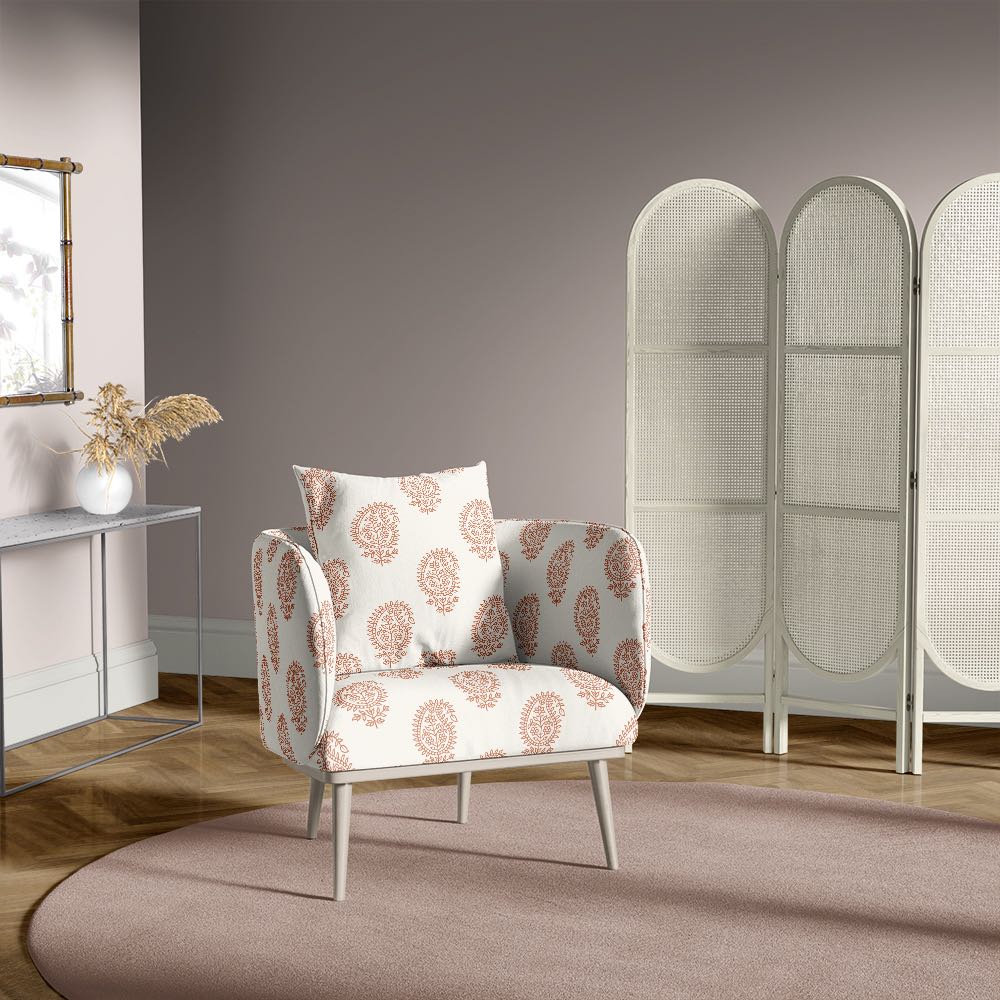 Chair covered in paisley henna upholstery fabric, placed in a muted mauve room with minimalist decor and wooden flooring