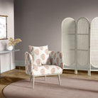 Chair covered in paisley henna upholstery fabric, placed in a muted mauve room with minimalist decor and wooden flooring