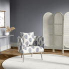 Chair in paisley navy blue upholstery fabric, styled in a modern grey room with a white screen divider and round rug
