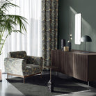 roomset featuring forest-toned leaf upholstery fabric on chair and curtains