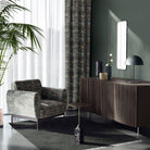 roomset featuring forest-toned leaf upholstery fabric on chair and curtains