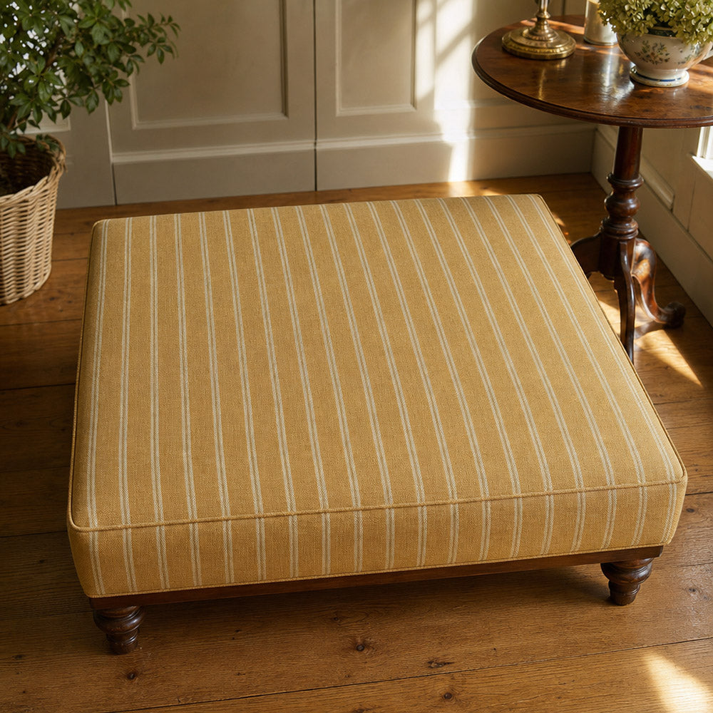 Suffolk Ochre striped upholstery fabric shown on a stool, warm yellow stripe fabric for statement upholstery