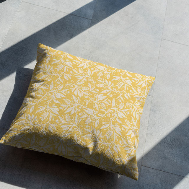 Cushion made with Oxford Leaf Ochre fabric displayed in sunlit interior