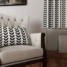 Black Scandi Stem linen curtain fabric styled as curtains and cushion in neutral armchair setting